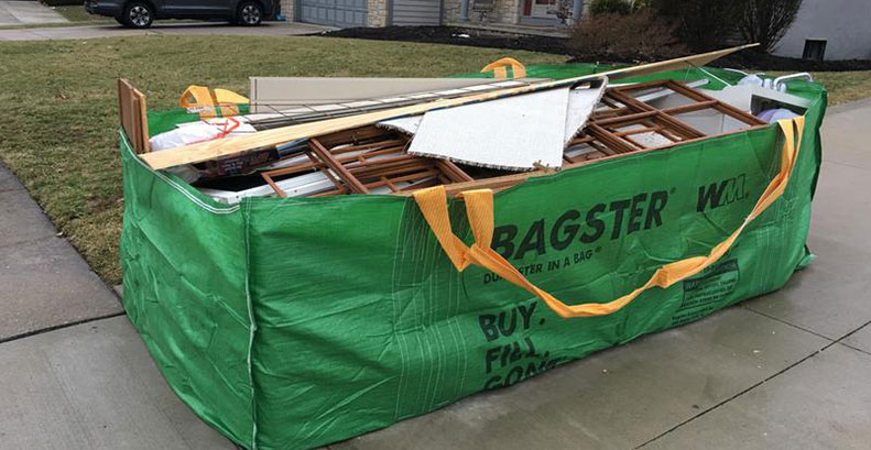 Bagster filled with wood, metal, cabinet doors, and a sink from a kitchen remodel.