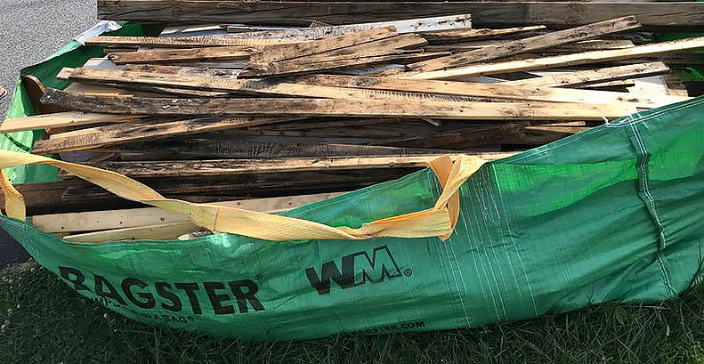 Bagster dumpster-in-a-bag filled with strips of old wood.