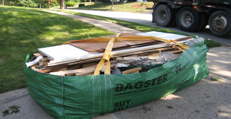One Bagster dumpster bag filled with PVC panels, wood panels, underlayment, and thin long strips of wood molding.