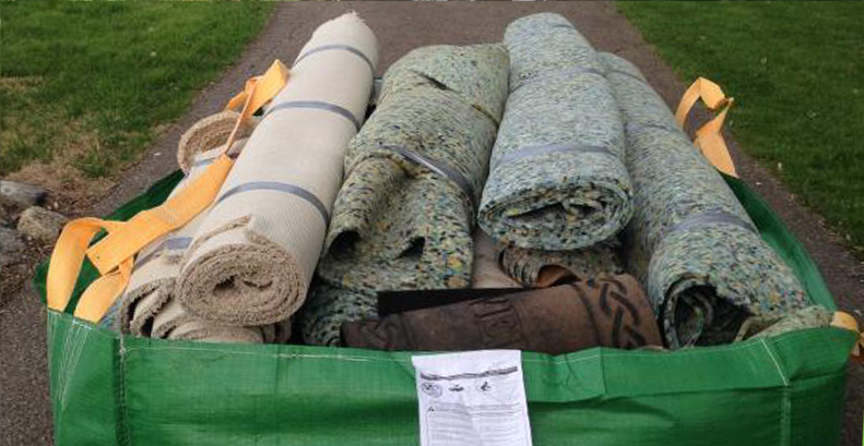Bagster dumpster bag filled with rolls of carpet and underlayment.